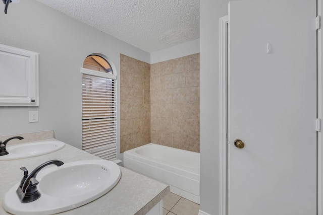 bathroom with tiled shower / bath, tile patterned floors, a textured ceiling, and double vanity