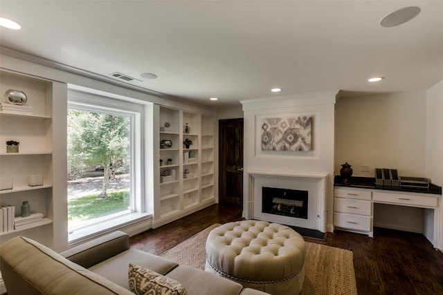 living room with built in features, dark hardwood / wood-style flooring, and a wealth of natural light