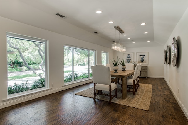 dining area with lofted ceiling, a notable chandelier, and dark hardwood / wood-style flooring