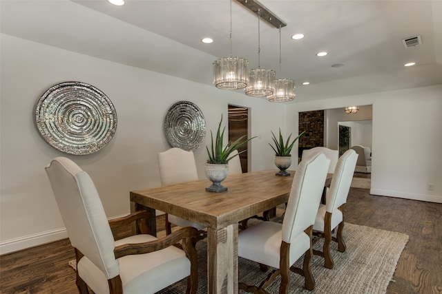 dining room featuring a notable chandelier, dark hardwood / wood-style flooring, and brick wall