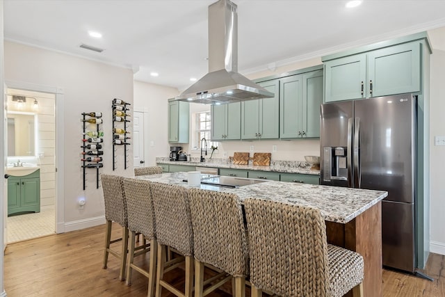 kitchen with stainless steel fridge, light hardwood / wood-style floors, a kitchen island, black electric cooktop, and island exhaust hood