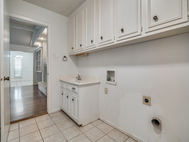 clothes washing area with cabinets, hookup for an electric dryer, sink, washer hookup, and light hardwood / wood-style flooring