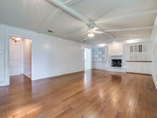 unfurnished living room featuring a brick fireplace, a textured ceiling, vaulted ceiling with beams, and wood-type flooring