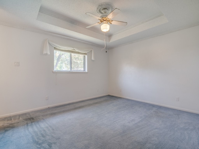 empty room with ceiling fan, a raised ceiling, and carpet floors