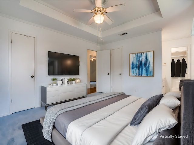 bedroom with ceiling fan, carpet flooring, and a raised ceiling