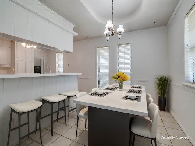 dining area featuring crown molding, a raised ceiling, light tile patterned floors, and an inviting chandelier