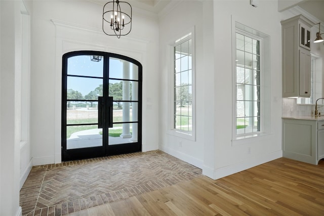 doorway featuring a wealth of natural light, crown molding, french doors, and a notable chandelier