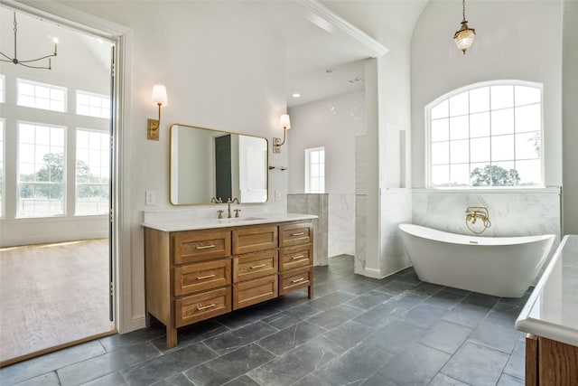 bathroom featuring vanity, tile walls, a chandelier, high vaulted ceiling, and a bathing tub