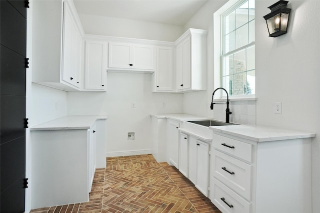 kitchen with light stone countertops, white cabinetry, plenty of natural light, and sink