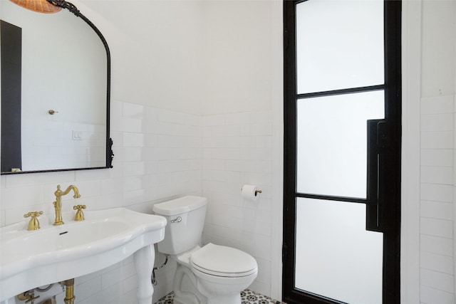 bathroom featuring sink, tile walls, and toilet