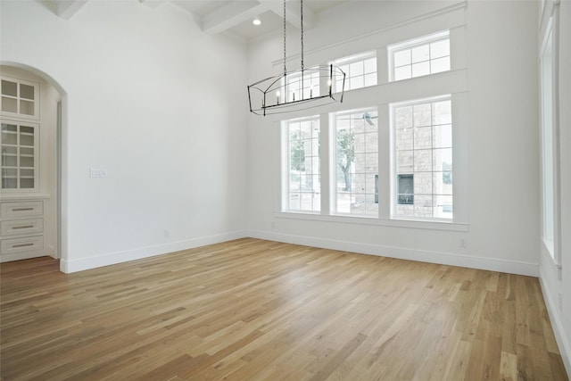 interior space with light wood-type flooring, beam ceiling, and a notable chandelier