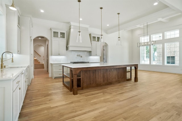 kitchen featuring sink, white cabinetry, light hardwood / wood-style flooring, hanging light fixtures, and a large island