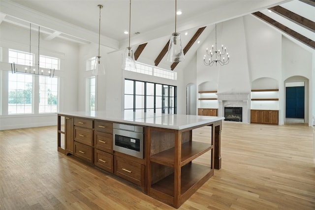 kitchen featuring a notable chandelier, pendant lighting, a center island, a towering ceiling, and a high end fireplace