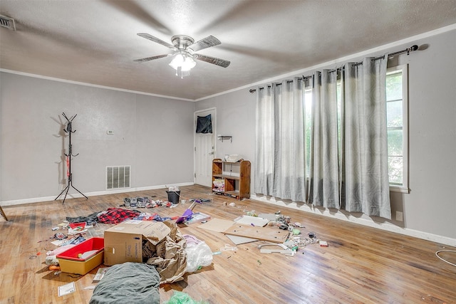 game room with hardwood / wood-style flooring, a textured ceiling, ornamental molding, and ceiling fan