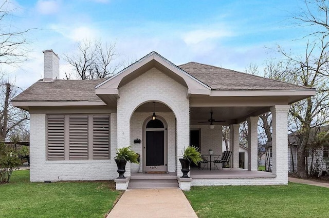 view of front of home with a front yard, ceiling fan, and covered porch