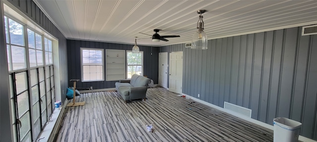 unfurnished sunroom featuring ceiling fan and a healthy amount of sunlight