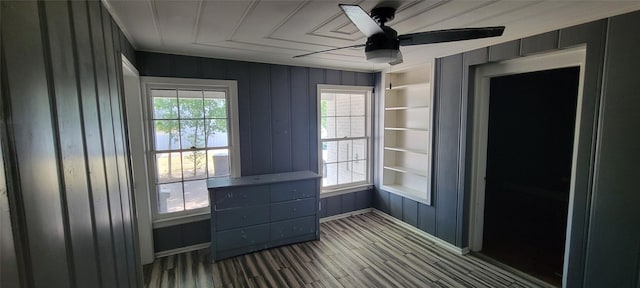 empty room with built in shelves, ceiling fan, and plenty of natural light