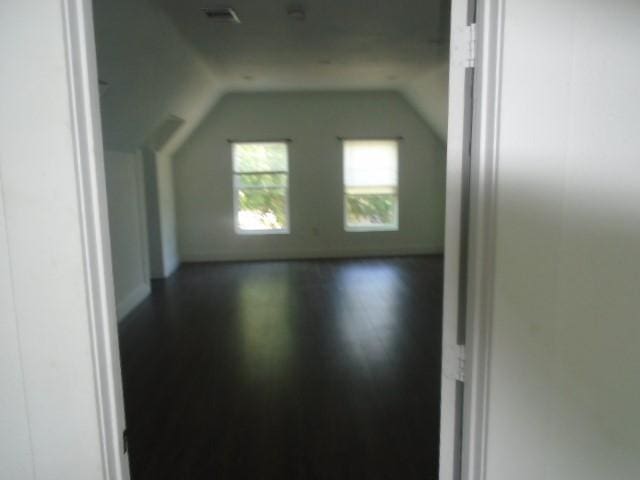 additional living space with vaulted ceiling and dark hardwood / wood-style floors