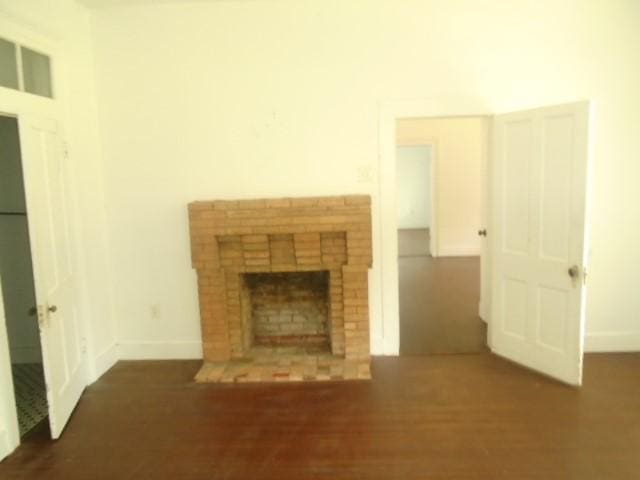 unfurnished living room with dark hardwood / wood-style flooring and a fireplace