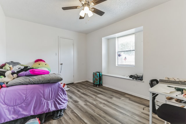 bedroom with a textured ceiling, wood-type flooring, and ceiling fan