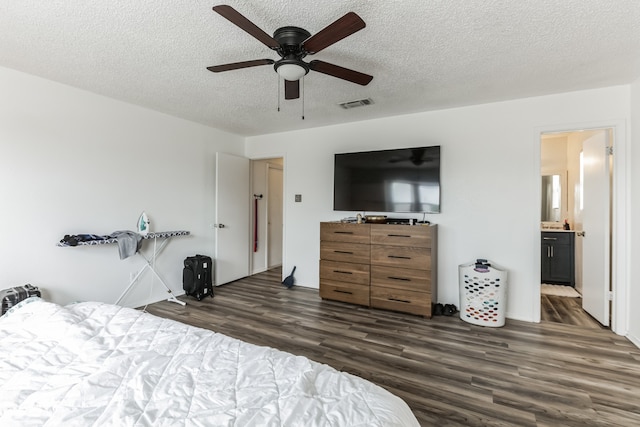 bedroom with ceiling fan, a textured ceiling, dark hardwood / wood-style flooring, and connected bathroom