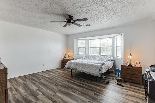 bedroom with a textured ceiling, multiple windows, hardwood / wood-style floors, and ceiling fan