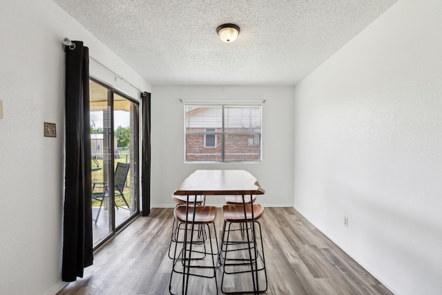 dining space with a textured ceiling, light hardwood / wood-style flooring, and a wealth of natural light