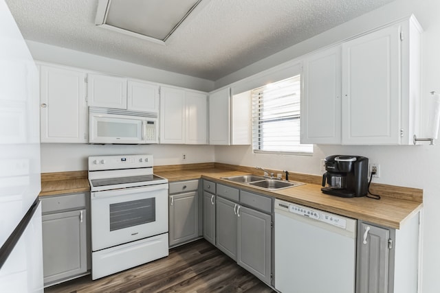 kitchen with white appliances, sink, a textured ceiling, dark hardwood / wood-style floors, and white cabinetry