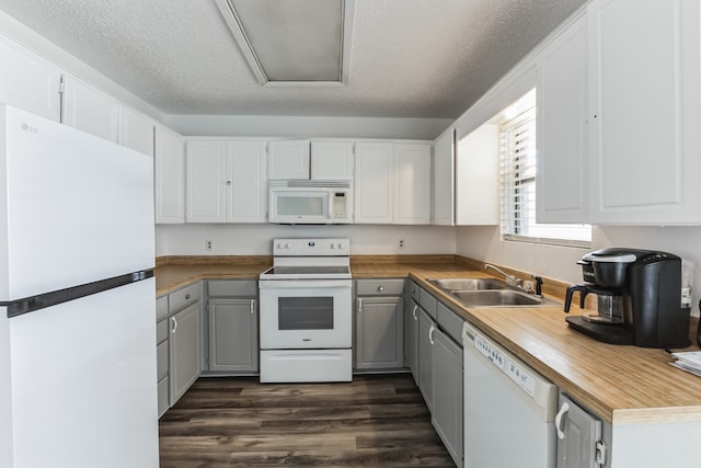 kitchen with white cabinetry, white appliances, a textured ceiling, dark hardwood / wood-style floors, and sink