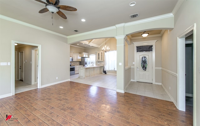 unfurnished living room with decorative columns, light tile patterned floors, ceiling fan with notable chandelier, sink, and ornamental molding