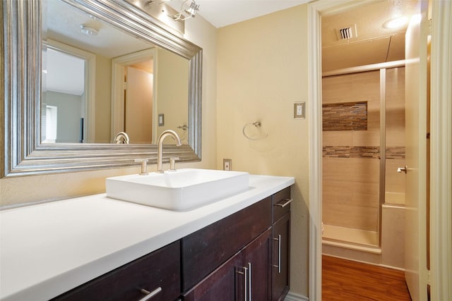 bathroom featuring hardwood / wood-style flooring, vanity, and walk in shower