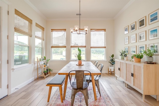 dining area with an inviting chandelier, light wood-type flooring, and ornamental molding