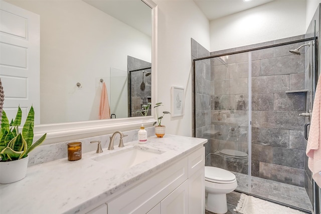 bathroom featuring a shower with door, vanity, and toilet