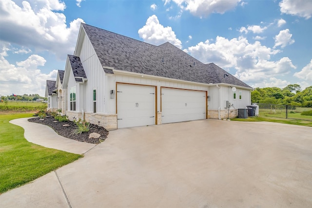 view of property exterior with a lawn, a garage, and central AC unit