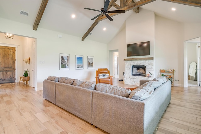 living room featuring ceiling fan, beam ceiling, high vaulted ceiling, a fireplace, and light wood-type flooring