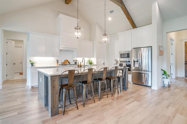 kitchen featuring high vaulted ceiling, stainless steel appliances, beam ceiling, and white cabinets