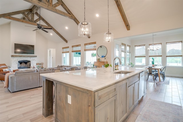 kitchen with a kitchen island with sink, sink, pendant lighting, and high vaulted ceiling