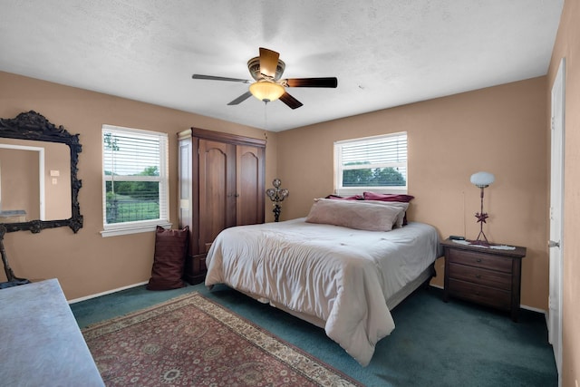 bedroom featuring multiple windows, a textured ceiling, ceiling fan, and dark colored carpet