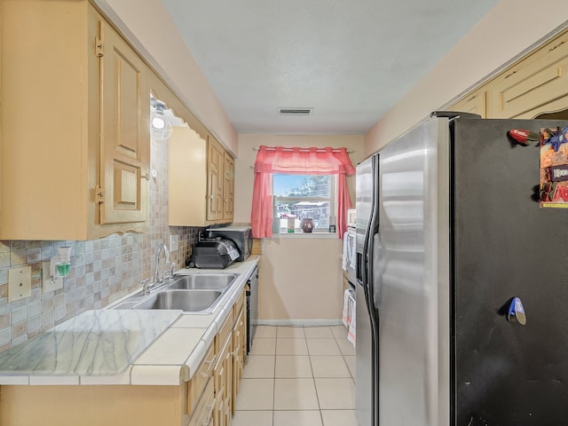 kitchen featuring tasteful backsplash, light brown cabinets, light tile patterned flooring, sink, and stainless steel refrigerator with ice dispenser