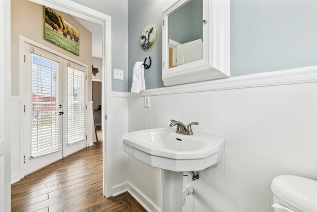 bathroom with french doors, toilet, and hardwood / wood-style floors