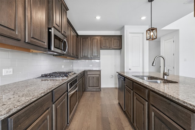 kitchen featuring decorative backsplash, light hardwood / wood-style flooring, pendant lighting, sink, and stainless steel appliances