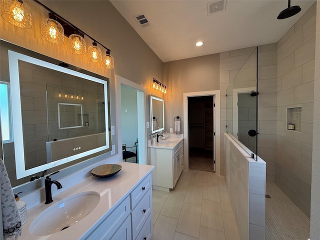 bathroom with vanity, a tile shower, and tile patterned floors