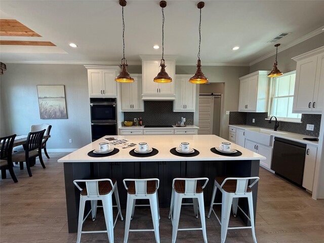 kitchen with a barn door, a kitchen island, white cabinets, and black appliances