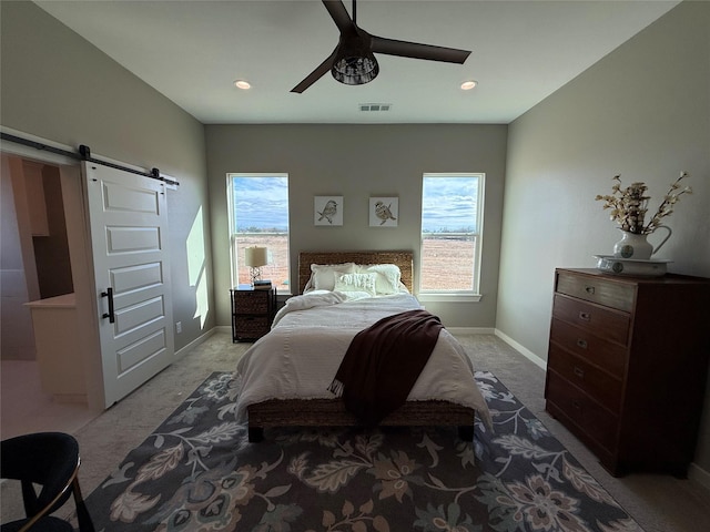 carpeted bedroom with a barn door and ceiling fan