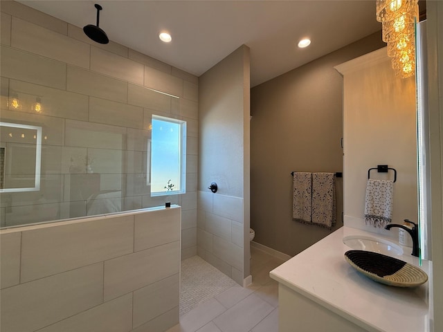 bathroom featuring a tile shower, vanity, tile patterned flooring, and toilet