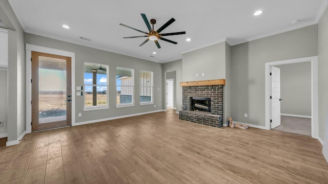 unfurnished living room featuring ceiling fan, a brick fireplace, crown molding, and light hardwood / wood-style flooring