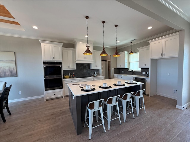 kitchen with a kitchen island, white cabinetry, a breakfast bar area, hanging light fixtures, and double wall oven