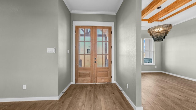 doorway with crown molding, wood-type flooring, and an inviting chandelier