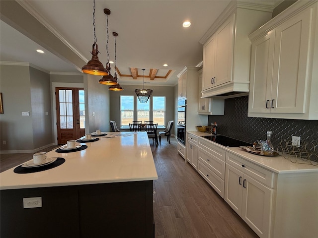 kitchen with pendant lighting, white cabinetry, a center island, ornamental molding, and black appliances