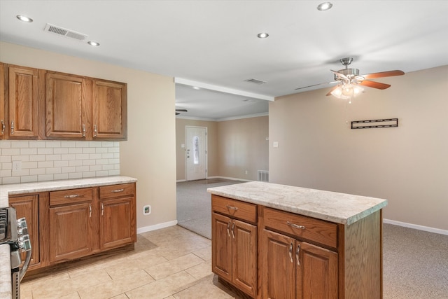 kitchen with ceiling fan, range, light stone counters, light colored carpet, and backsplash